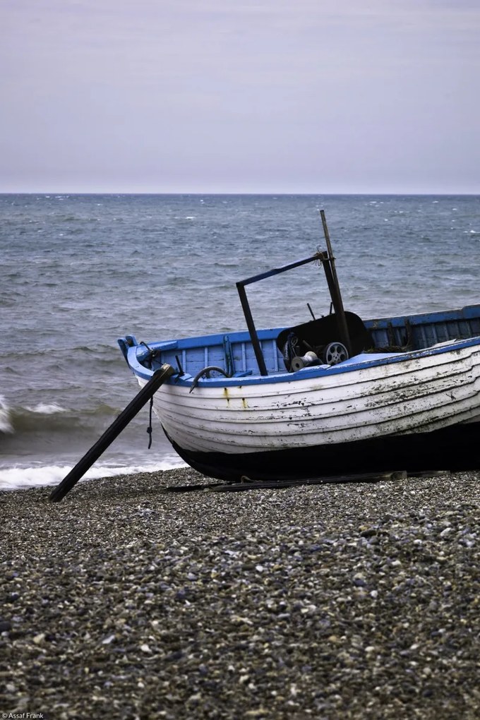 Poszter 20x30cm Régi halászcsónak a kavicsos tengerparton, Assaf Frank