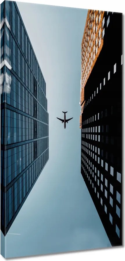 Vászonkép 55x115 Repülőgép az épületek között
