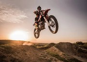 Fotográfia Motocross rider performing high jump at sunset., skynesher