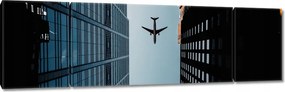 Vászonkép 170x50 Repülőgép az épületek között