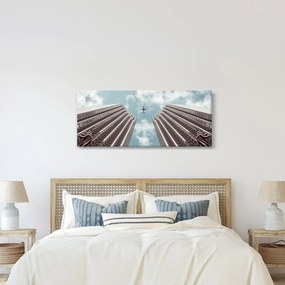Repülőgép az épületek között képe (120x50 cm)