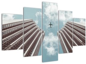 Repülőgép az épületek között képe (150x105 cm)