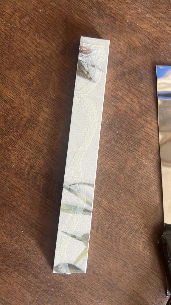 Kivágott csempére utólag ráragasztott fémcsík,szilikon alapú ragasztóval.
Valószínűleg,1 év múltva gondolkodhatok,hogy a 480ezres nettó árú csempe közé beépített fém dísz,mikor fog lepotyogni.Ha nem rontottunk volna el egy vágást fel sem tűnt volna,csak ha kézzel kopogtatom és érzésre is üreges,természetesen,miután be lett építve.