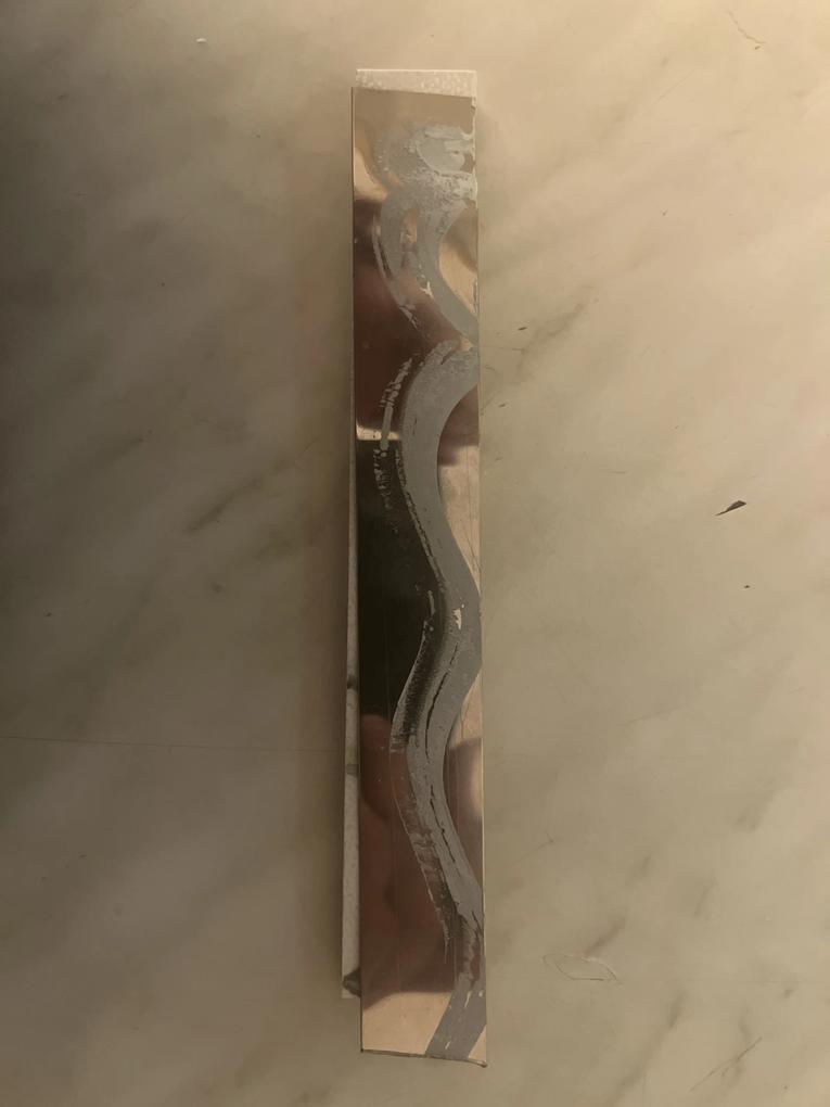 Kivágott csempére utólag ráragasztott fémcsík,szilikon alapú ragasztóval.
Valószínűleg,1 év múltva gondolkodhatok,hogy a 480ezres nettó árú csempe közé beépített fém dísz,mikor fog lepotyogni.Ha nem rontottunk volna el egy vágást fel sem tűnt volna,csak ha kézzel kopogtatom és érzésre is üreges,természetesen,miután be lett építve.