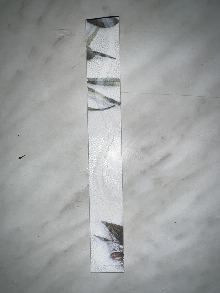 Kivágott csempére utólag ráragasztott fémcsík,szilikon alapú ragasztóval.
Valószínűleg,1 év múltva gondolkodhatok,hogy a 480ezres nettó árú csempe közé beépített fém dísz,mikor fog lepotyogni.Ha nem rontottunk volna el egy vágást fel sem tűnt volna,csak ha kézzel kopogtatom és érzésre is üreges,természetesen,miután be lett építve.